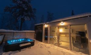 a building with a tub in the snow at night at Northern Lights Ranch in Köngäs