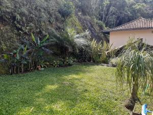 a yard with grass and a house and trees at Loft Aconchego da Serra in Petrópolis