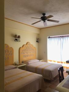 a bedroom with two beds and a ceiling fan at Hotel Maria Mixteca in Santa Cruz Huatulco