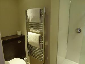 a bathroom with a shower and a toilet and towels at Boathouse Hotel in Hythe