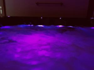una piscina de luz púrpura en una habitación oscura en Une Pause Douceur - Suite Orchidée, en Eyguières