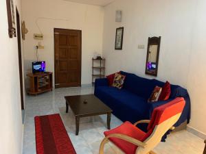 uma sala de estar com um sofá azul e uma mesa em Lovely Garden Villas em Pantai Cenang