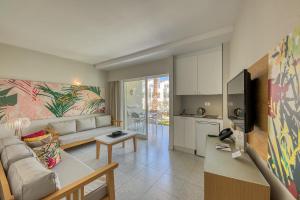 a living room with a couch and a kitchen at Apartamentos LIVVO Koala Garden in Maspalomas