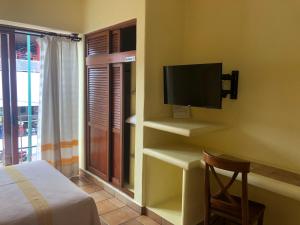 a bedroom with a bed and a tv on a wall at Hotel Maria Mixteca in Santa Cruz Huatulco