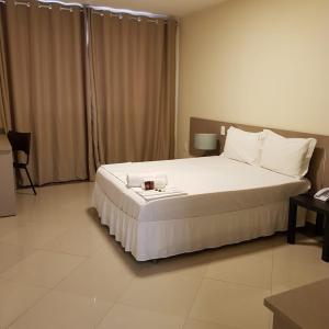 a bedroom with a large white bed with a candle on it at Paracambi Top Hotel in Paracambi