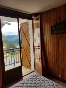 1 dormitorio con puerta que da a un balcón en Le Petit Chalet, en Auron