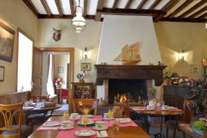 a dining room with tables and a fireplace at Hostellerie de la Motte jean in Saint-Coulomb