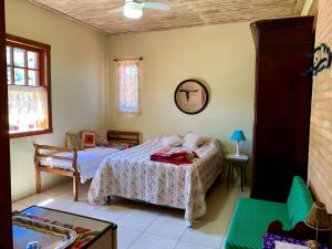 um quarto com uma cama e uma cadeira em Pouso Flor de Manacá em Tiradentes