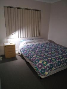 a bedroom with a bed with a bedspread and a window at Near Train Station in Perth