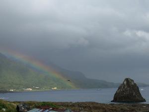 a rainbow over a body of water with a bird at 蘭嶼月台民宿 in Lanyu