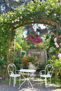 two chairs and a table under an arch with flowers at Hostellerie de la Motte jean in Saint-Coulomb