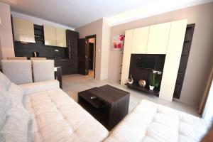 sala de estar con sofá blanco y TV en Menada Harmony Suites Apartments, en Sunny Beach