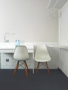 dwa białe krzesła siedzące obok blatu kuchennego w obiekcie Nu Hotel w Łodzi