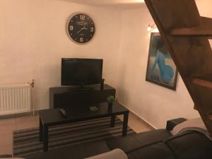 uma sala de estar com televisão e um relógio na parede em studio cosy em Gesves