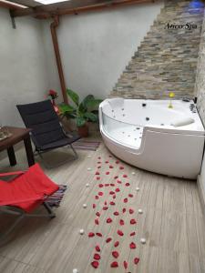 una vasca da bagno seduta su un pavimento in legno con petali di rosa rossa di Casas Toya Jacuzzi a Uceda