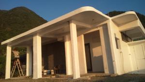 Un uomo in piedi davanti a una casa bianca di 蘭嶼老鍋蓋民宿 a Lanyu