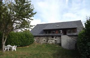 uma casa de pedra com uma mesa e cadeiras em frente em Gite 3 étoiles dans une grange rénovée - Cantal Emotions Valette - Auvergne em Valette