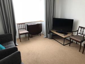 a living room with a tv and two chairs and a table at Jo's Rest in Birmingham