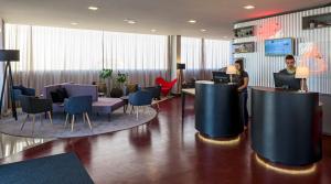 a lobby with two people standing in a waiting room at ibis Styles Franca in Franca