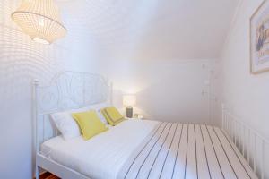 ein weißes Schlafzimmer mit einem weißen Bett und gelben Kissen in der Unterkunft Light Filled Typical Apartment at Alfama, By TimeCooler in Lissabon