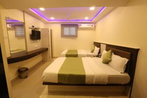 a bedroom with two beds and a purple lighting at Hotel Happyland in Mumbai