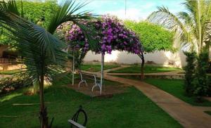 un parque con árboles con flores púrpuras. en Hotel Winner, en Barretos