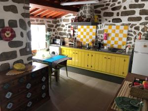 a kitchen with yellow cabinets and a stone wall at Casa Auri in Faial da Terra
