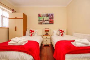 2 camas en una habitación con sábanas rojas y blancas en Harris Guest Accommodation, en Oxford