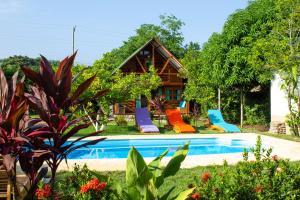 a house with a pool with colorful chairs next to it at Nubá Boutique Hostel Palomino in Palomino