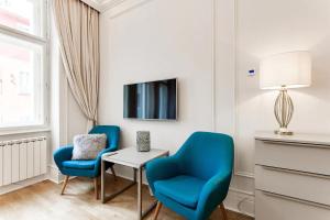 a living room with two blue chairs and a table and a tv at Prague Centre Armani Apartment in Prague