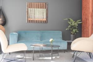 a blue couch in a living room with two chairs and a table at L'Anderenis Boutique Hôtel in Andernos-les-Bains