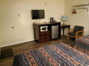 a hotel room with two beds and a tv at Battlefords Inn in North Battleford