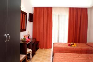 a bedroom with a bed and a window with red curtains at Paradise Apartments in Laganas