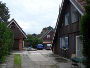 a driveway between two houses with cars parked in the yard at Skruzdėlynas in Nida