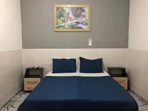 1 dormitorio con 1 cama azul y 2 mesitas de noche en Pousada El Shaddai en Campos dos Goytacazes