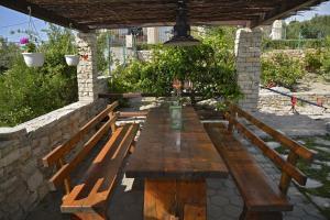 una mesa de madera y bancos bajo una pared de piedra en Apartment Toni - with pool and view, en Maslinica
