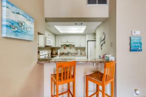 kuchnia z dwoma pomarańczowymi krzesłami przy ladzie w obiekcie Sand Dollar E205 w mieście Pensacola Beach