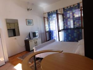 Donje Selo的住宿－Apartments Lado - 230 m from sea，一间卧室配有一张床、一张桌子和一台电视。