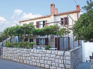 a house with a stone retaining wall and a stone fence at Apartment Sova - 20m from beach in Postira