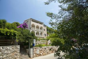 a house on a stone wall with purple flowers at Apartment Ante-50m from beach in Smokvica