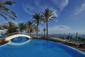 a swimming pool with a bridge and palm trees at Pestana Grand Ocean Resort Hotel in Funchal