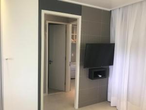 a room with a flat screen tv and a mirror at Flat Beach Class Muro Alto 4307 in Porto De Galinhas