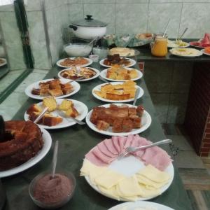 a table full of different types of food on plates at Hospedaria de Maria in Tiradentes +43 photos