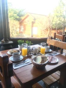 Solares Del Sur في إل كالافاتي: طاولة خشبية بها طعام وكؤوس من عصير البرتقال