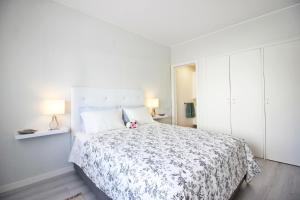 a white bedroom with a large bed with a pink teddy bear on it at T1 Casino Estoril in Estoril