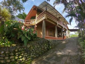 a house with a balcony on top of a stone wall at Hospedaje La Naciente in Turrialba