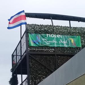 una señal en la parte superior de un edificio con una bandera en Rancha Azul Inn, en Alajuela