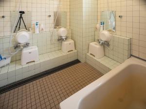 a bathroom with two urinals and a bath tub at Shimanoyado Rebunshiri in Rebun