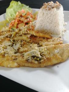 un plato blanco con un trozo de comida con arroz y lechuga en Hotel Cocotal, en Isla Grande