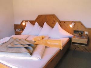 a bed with a wooden headboard and pillows on it at Ferienhotel Sunshine in Berg im Drautal